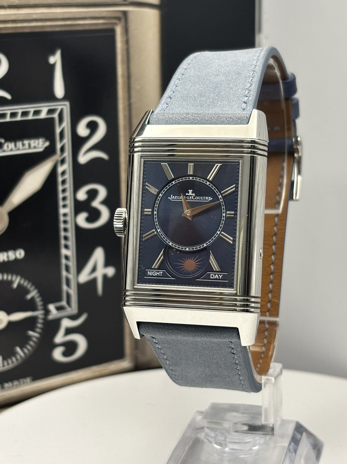 Luxury watch with blue strap on a stand, brand name visible
