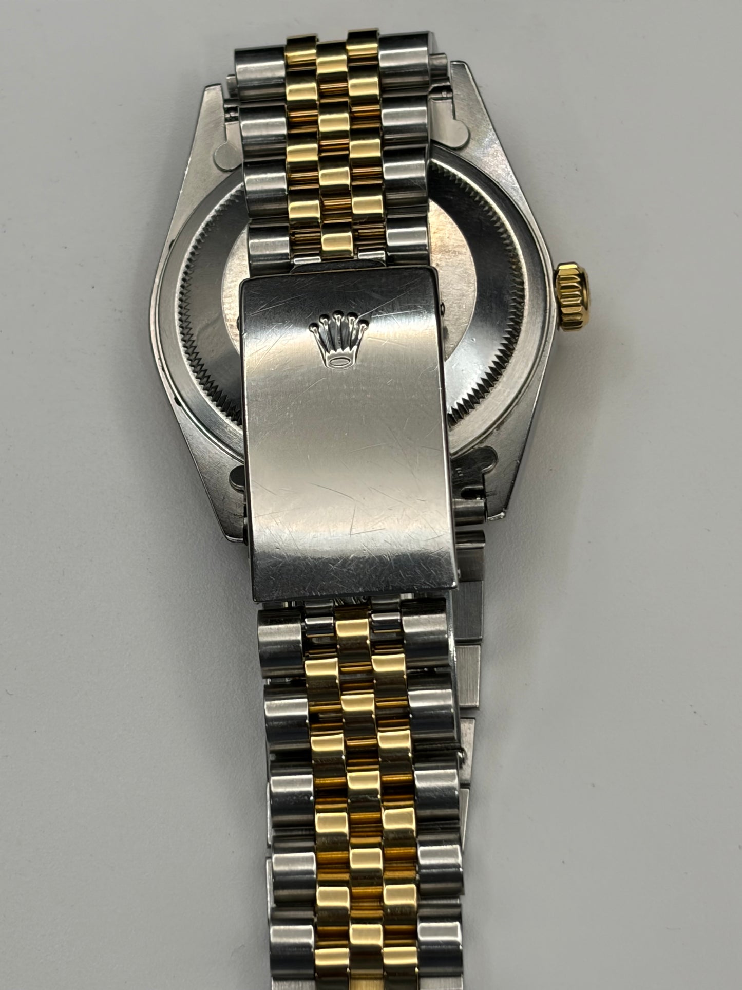 Close-up rear view of a two-tone metal wristwatch with a silver-toned case and bracelet featuring gold-toned links, shown on a plain light background.