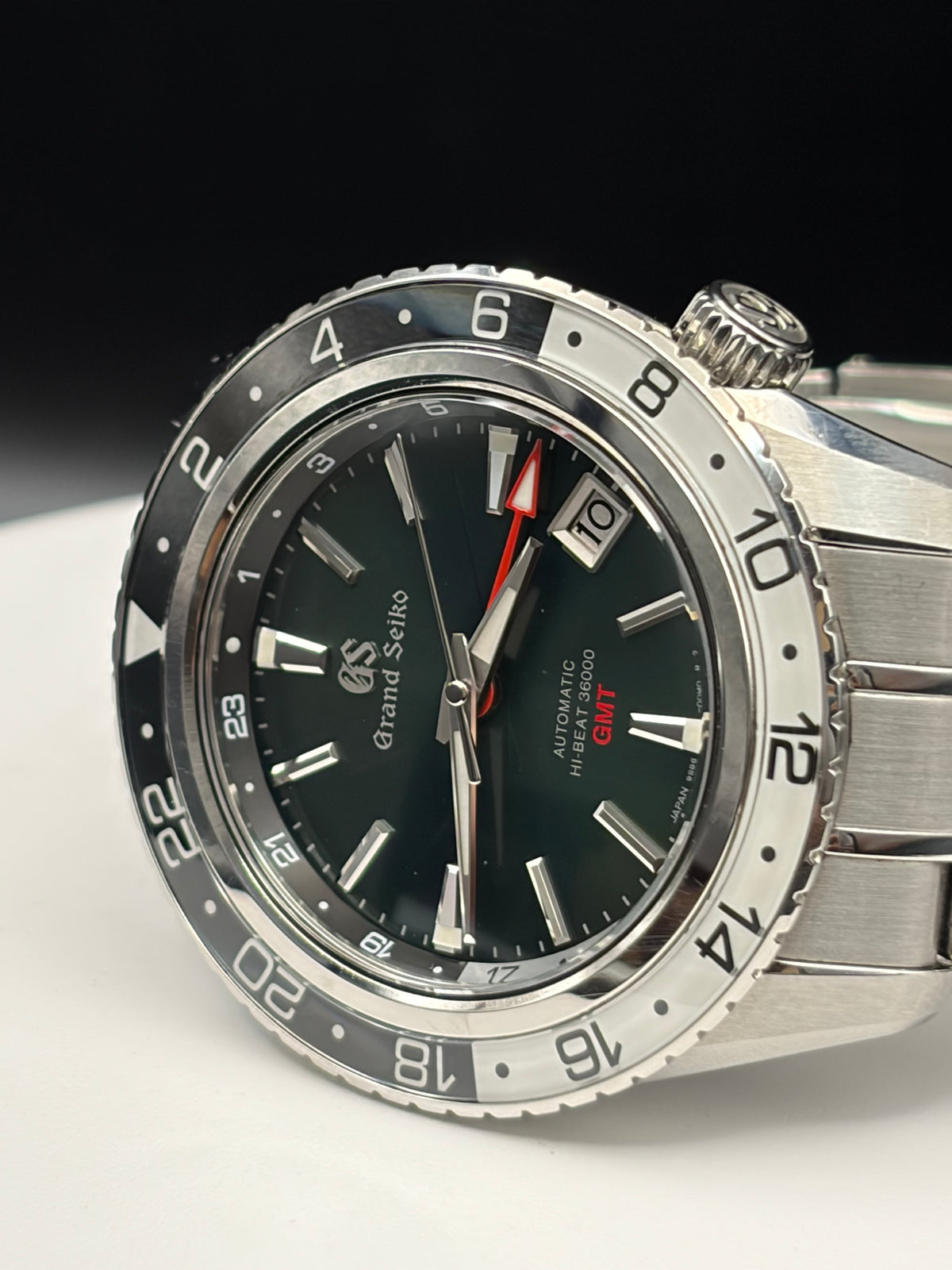 automatic dive watch with a stainless steel bracelet, featuring a dark green dial, a silver bezel with a black 24-hour scale, and a date window at 3 o'clock.