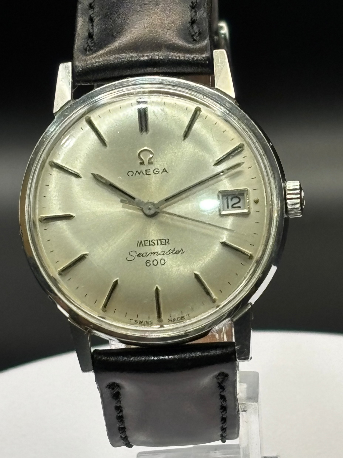 Vintage Omega watch with black leather strap on a dark background