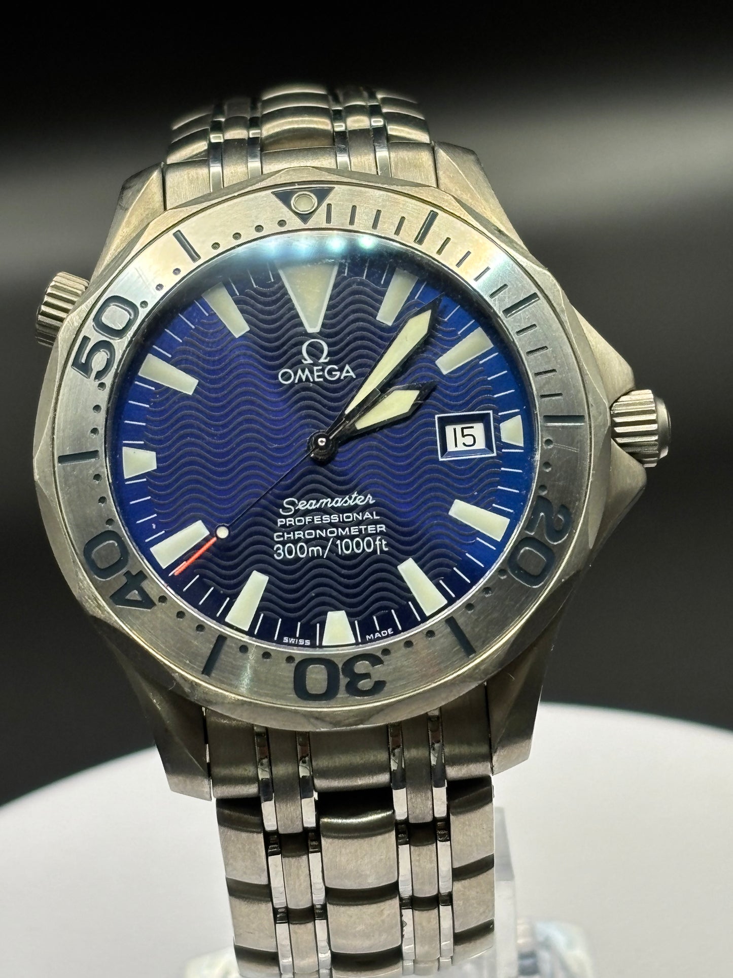 Silver Omega watch with blue face on a dark background