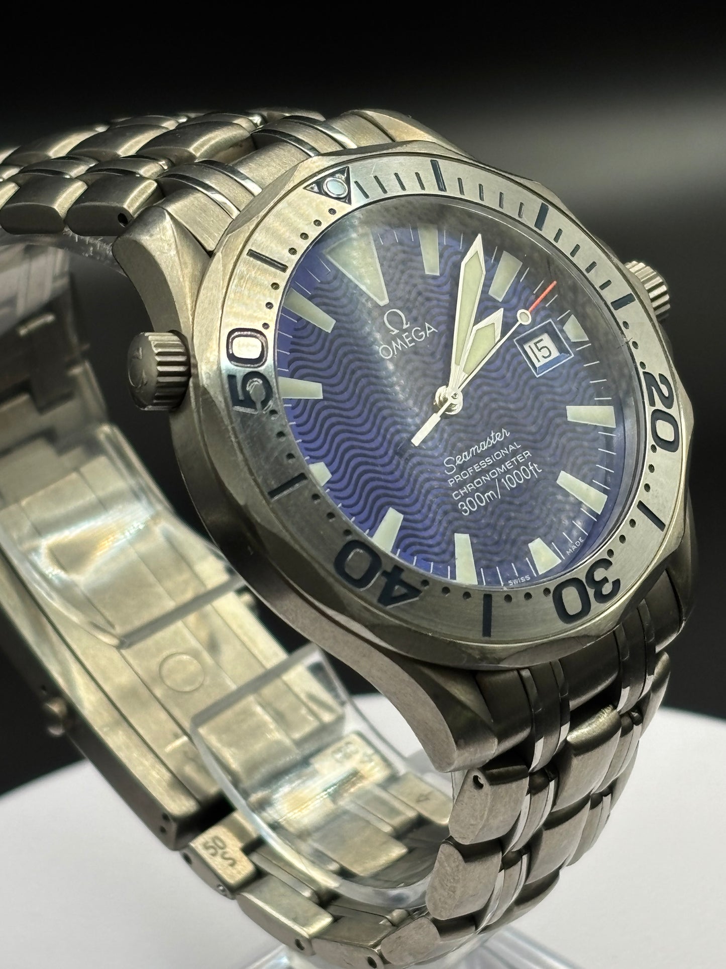 Omega watch with blue dial and metal bracelet on a reflective surface
