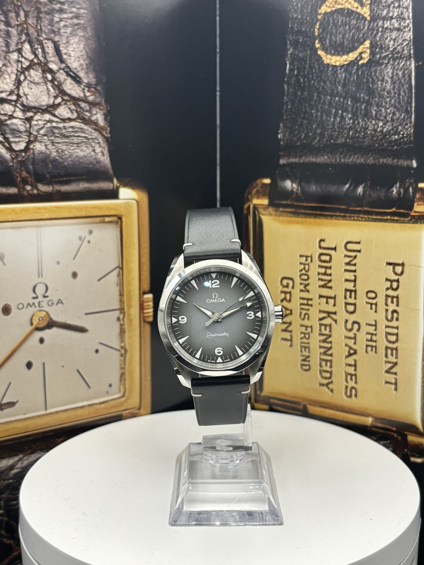 Omega watch on a stand with vintage Omega packaging in the background