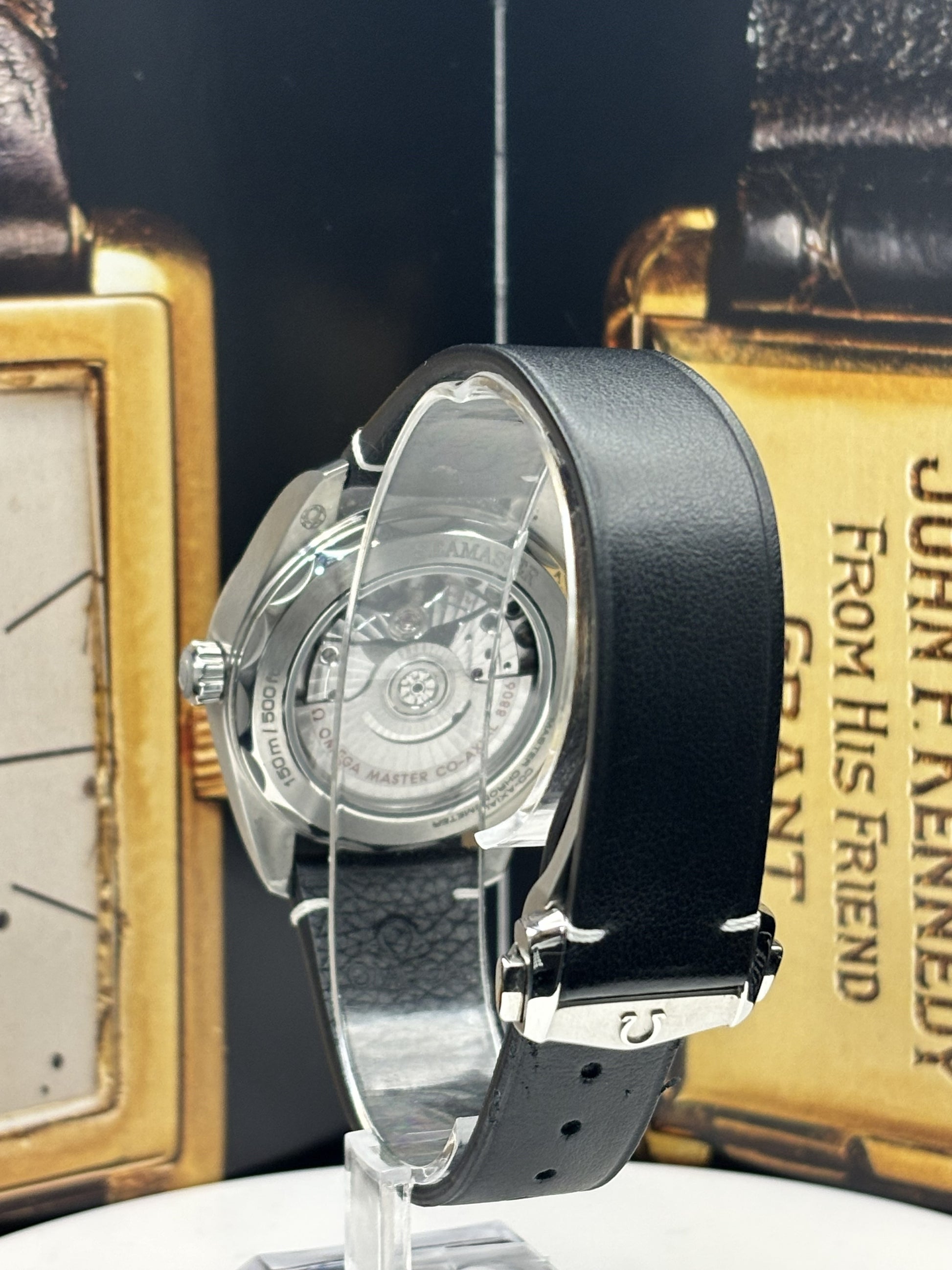 Watch with black strap on a stand against a vintage book background