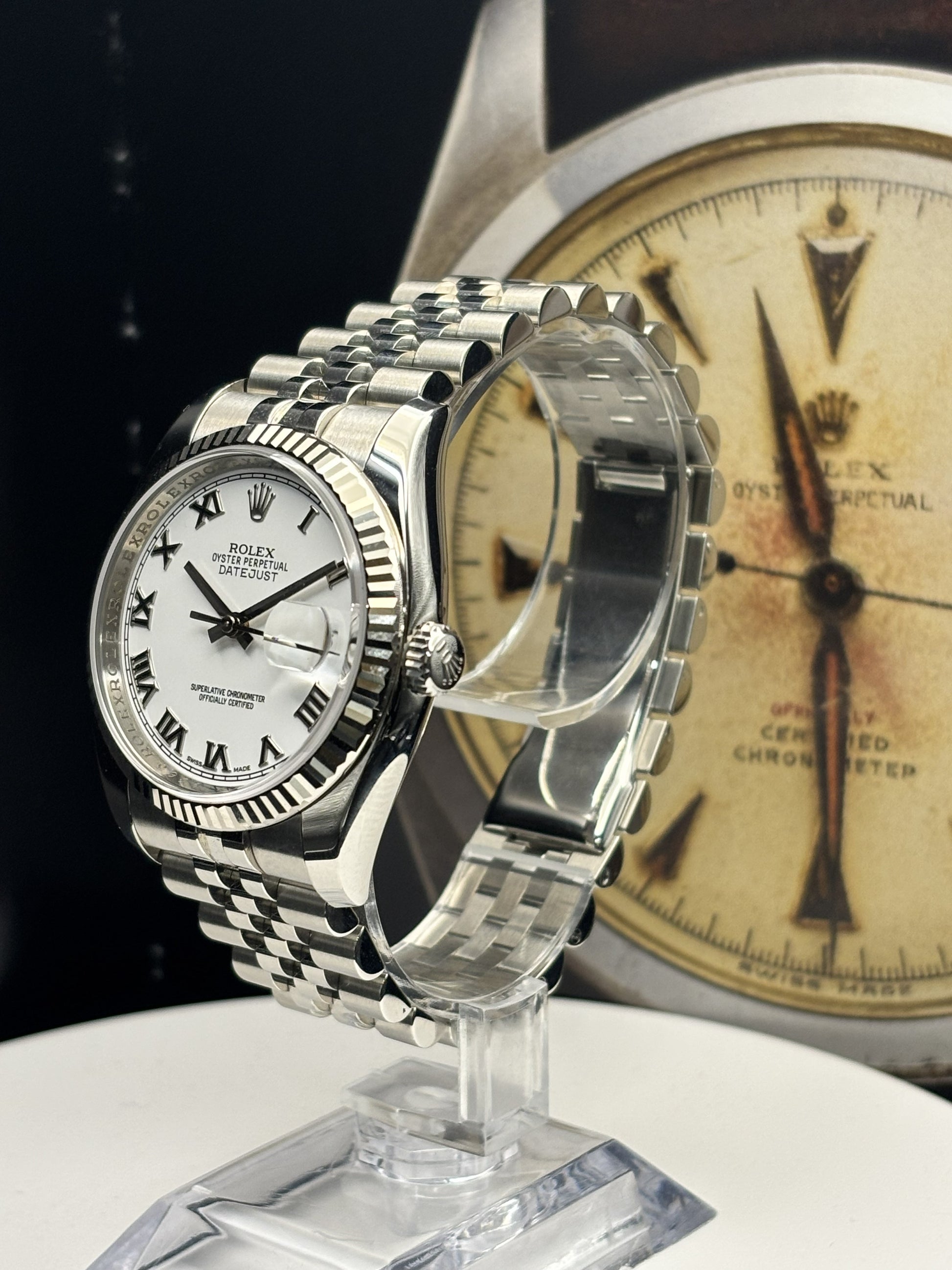 Silver watch on a stand with a blurred vintage-style watch in the background
