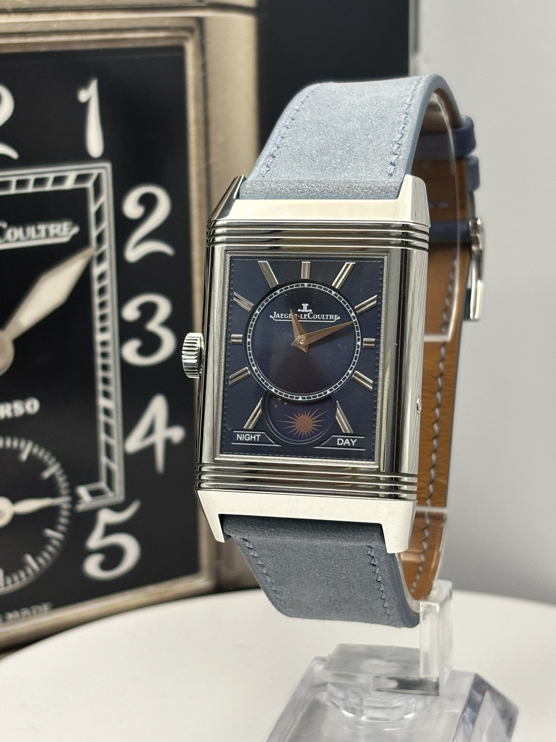 Luxury watch with blue strap on a stand, brand name visible
