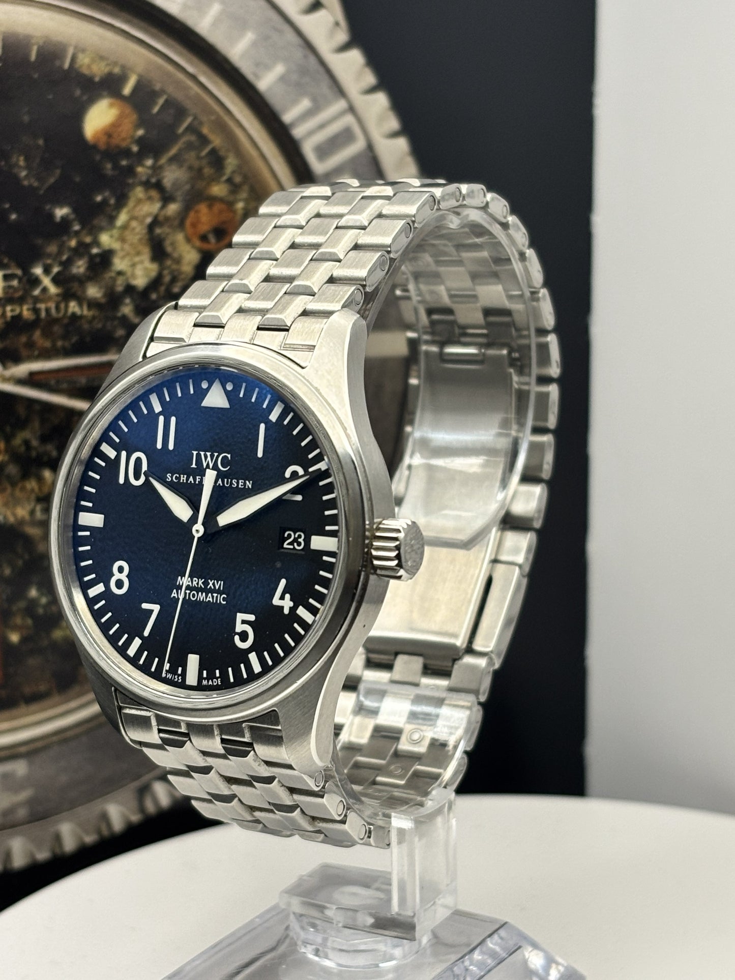 Silver watch with blue dial on a stand against a dark background