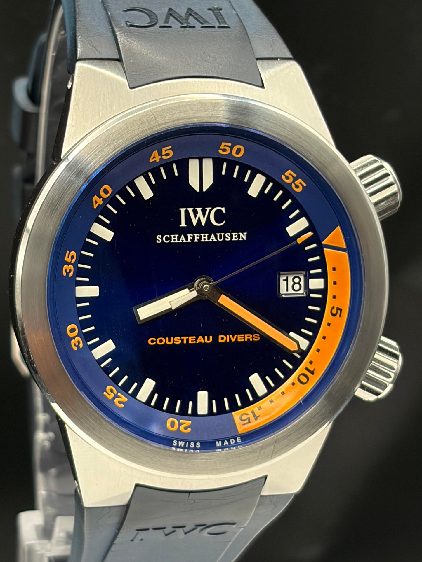 IWC Schaffhausen Cousteau Divers wristwatch with a silver stainless steel case, deep blue dial, orange accents, and a gray rubber strap.