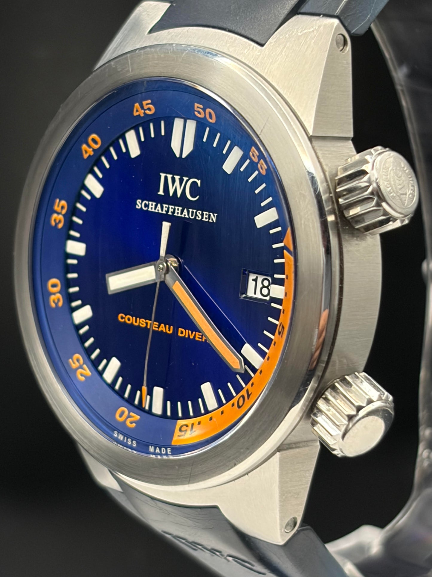 Close-up of an IWC Schaffhausen Cousteau Diver wristwatch with a blue dial, orange accents, and a brushed stainless steel case.