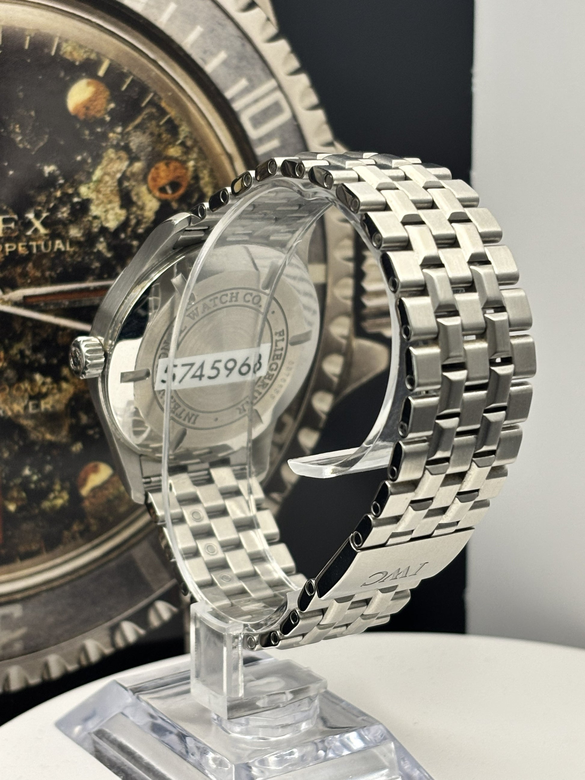 Silver watch on a stand with a detailed face in the background
