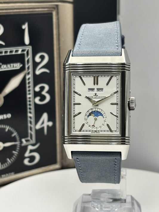 Luxury watch with gray strap on a white surface, with a blurred background