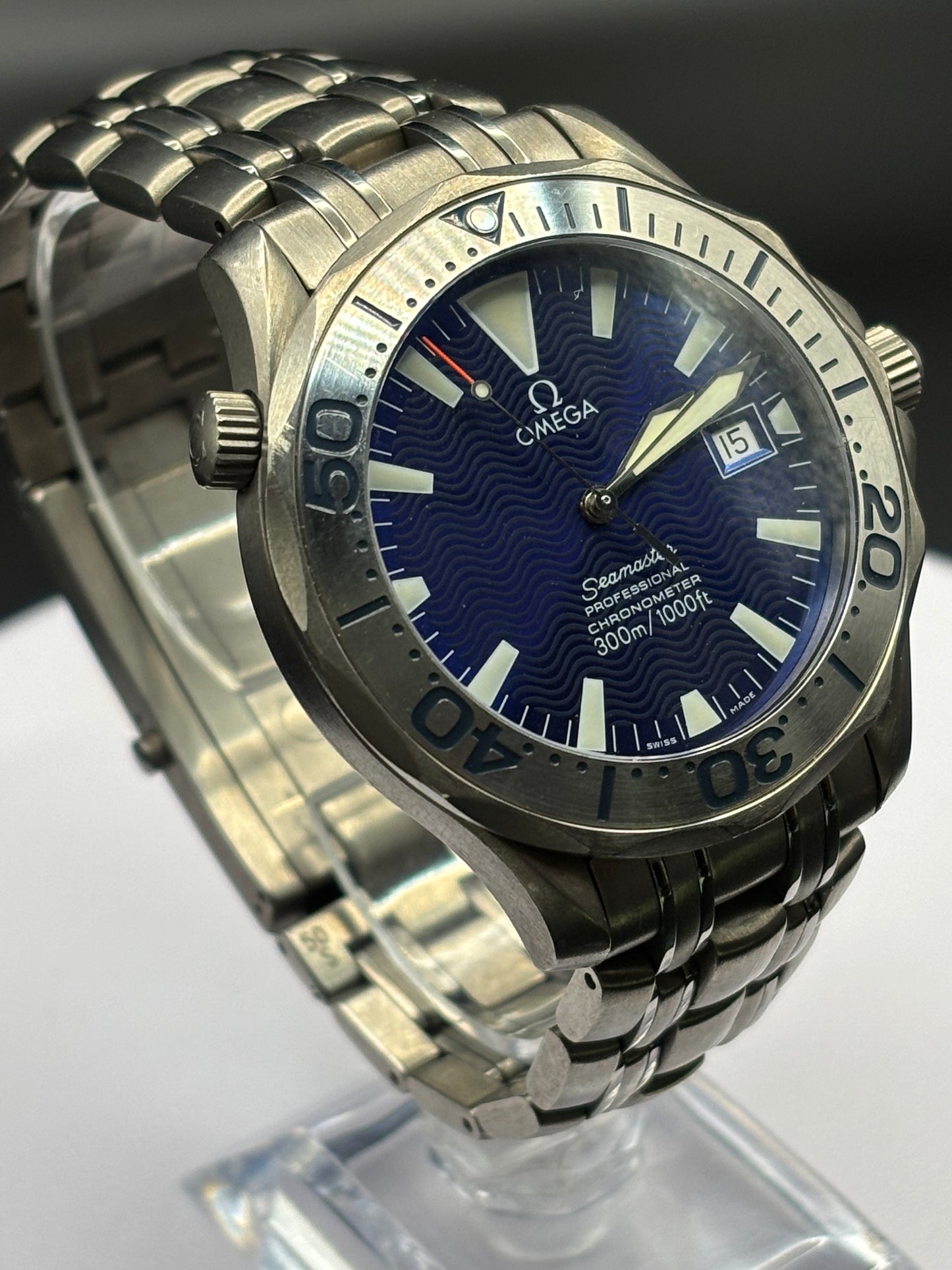 Silver Omega watch with blue dial on a clear stand