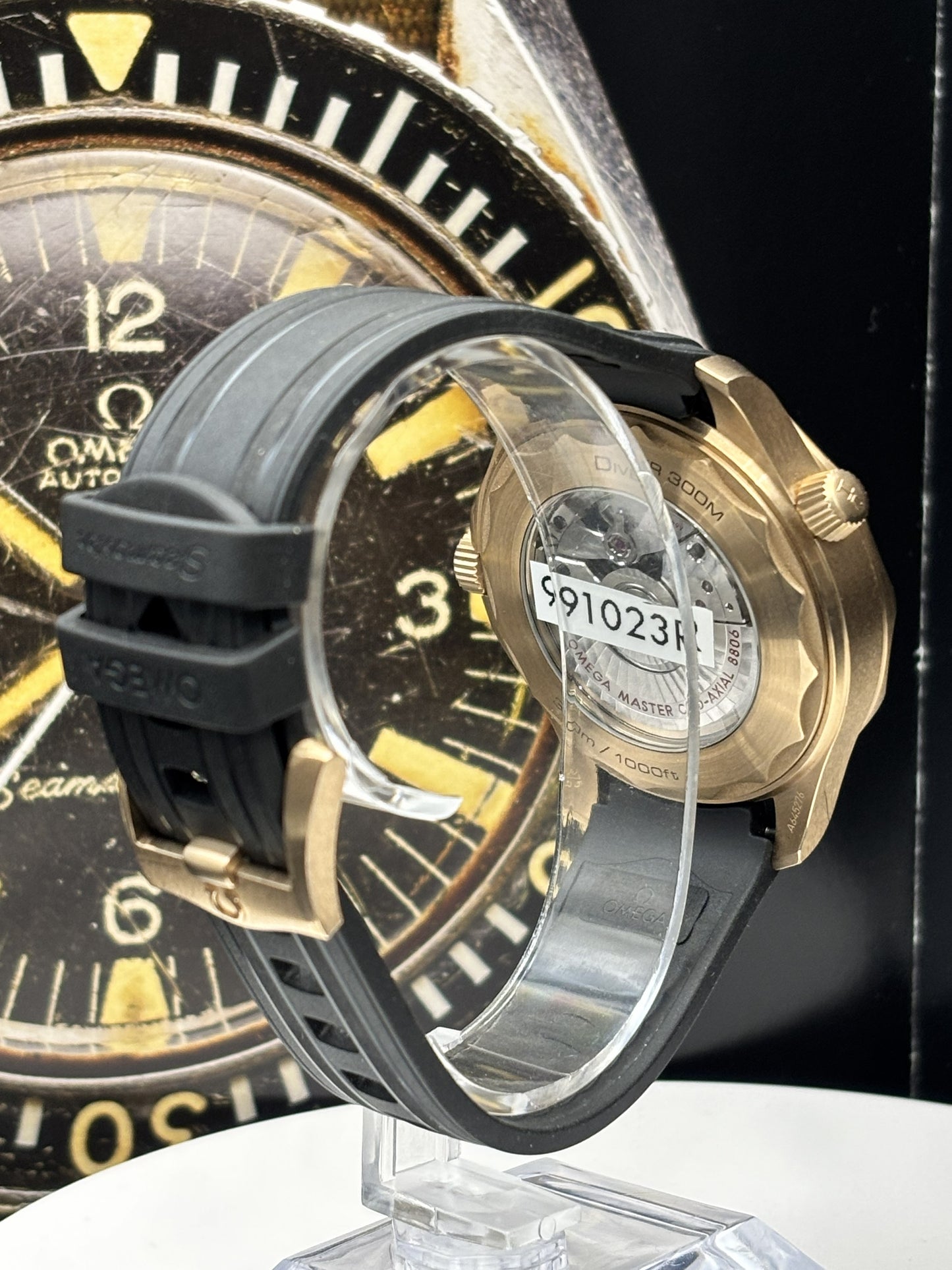 Close-up of a black and gold watch with a clear case back showing the Omega brand.
