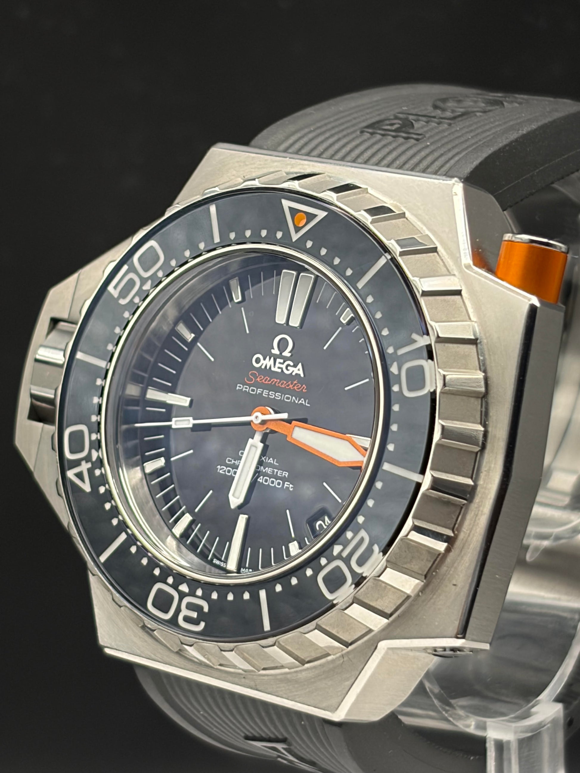 Omega Seamaster Professional diver watch with a silver-tone stainless steel case, black bezel and dial, and orange accents, shown close-up on a dark background.