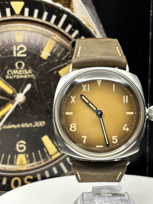 Two vintage watches, one with a brown face and leather strap, the other with a black face and gold accents, on a dark background.