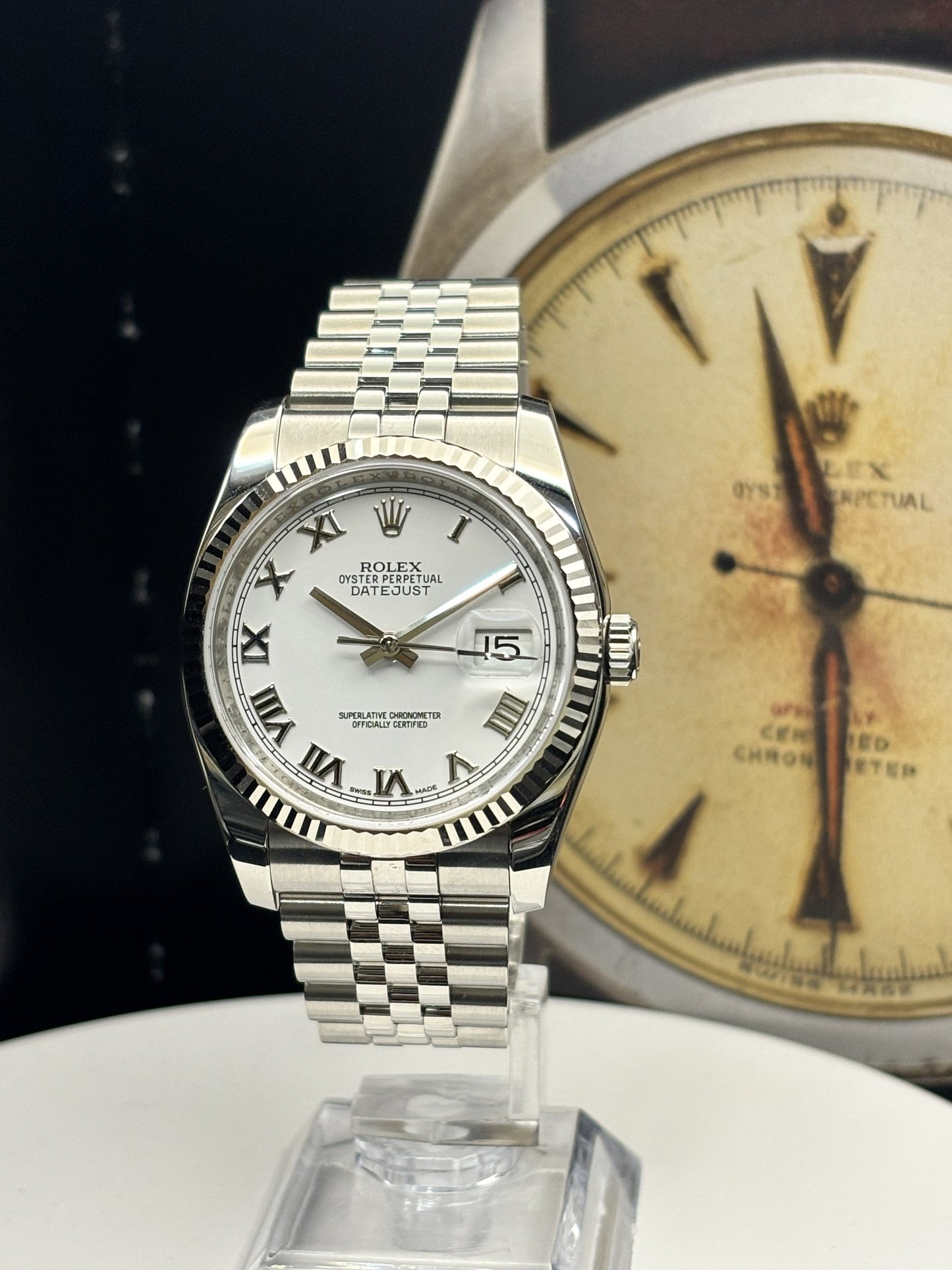 Silver watch with white face on a stand, vintage Rolex background