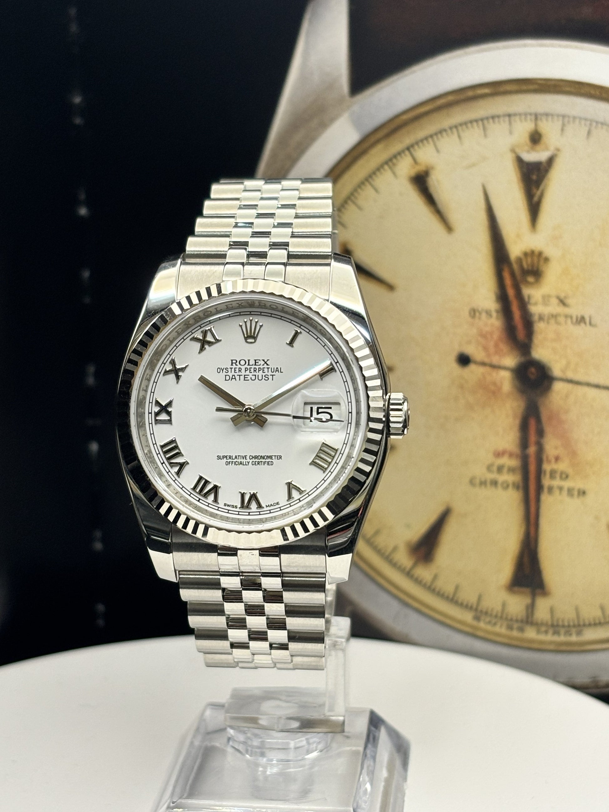 Silver watch with white face on a stand, vintage Rolex background